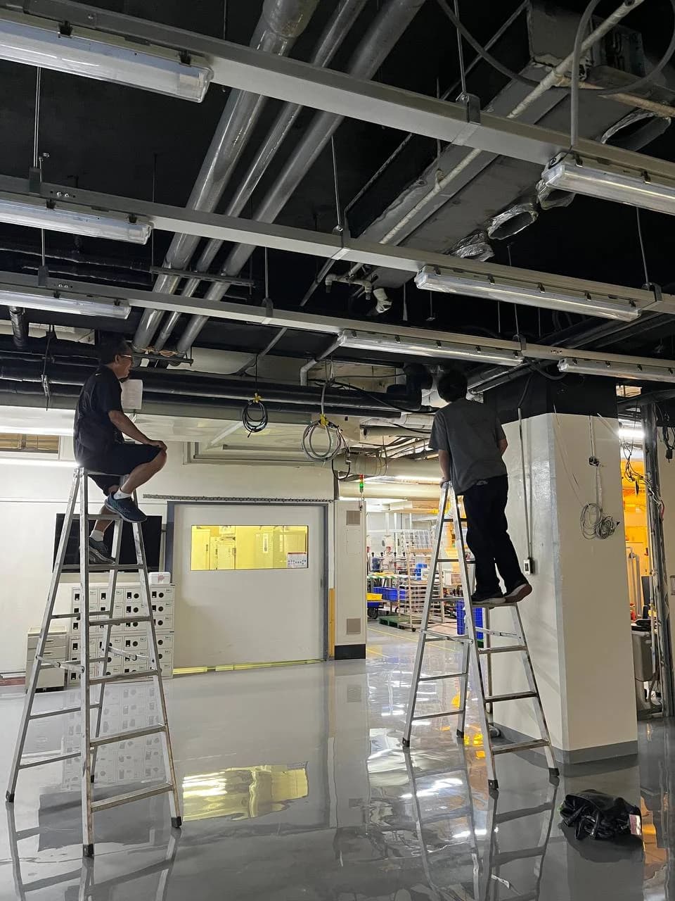 梁下管線、燈具與支架交錯的廠房現勘。
